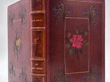 an old book with a rose design on the cover and a gold trim