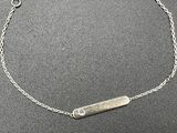a close up of a silver bracelet with a bar on it