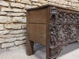 a wooden chest with carvings on it in front of a stone wall
