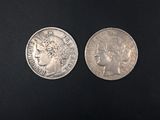 two silver coins on a black surface, one of which has a woman ' s head and the other of