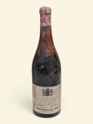 une vieille bouteille de vin posée sur une surface blanche