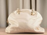 a white purse sitting on a table with a curtain behind it
