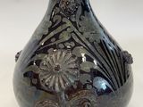 a black vase with a floral design on it
