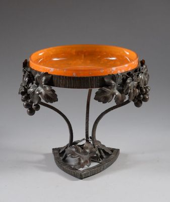 an orange glass bowl on a metal stand with flowers and leaves