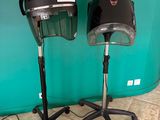 pair of black hair dryers on stands in front of a green wall