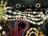 many different beads and necklaces on a black table