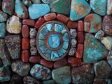 an image of a turquoise and red stone clock surrounded by rocks