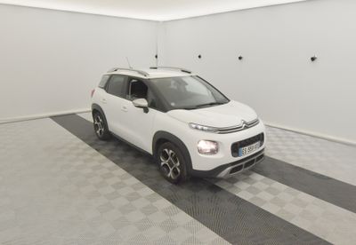 La petite voiture blanche est garée dans le garage, sur le sol à carreaux.