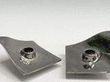 two pieces of silver metal on a white surface