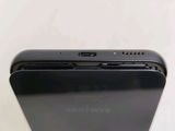 the back of a black cell phone sitting on top of a white table