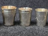 six vases en argent sont alignés sur une surface noire