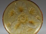 yellow glass plate with flowers and leaves on it on a stand