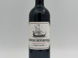 the bottle of red wine is sitting on a white surface