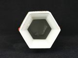 a close up of a small white vase on a black surface