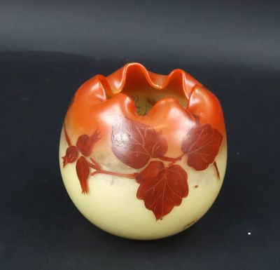 an orange and white vase with red leaves on it
