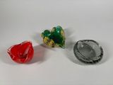 three different colored glass objects on a white surface