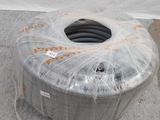 une grosse bobine de fil métallique enveloppée dans du plastique, posée par terre