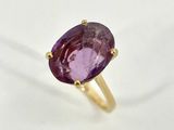 a close up of a purple stone ring on a white surface