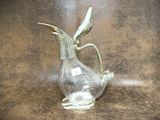 a glass vase with a bird on it on a brown surface