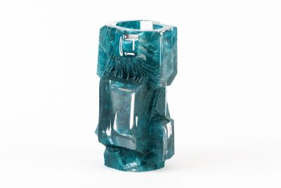 un vase bleu orné d'un visage, posé sur une surface blanche