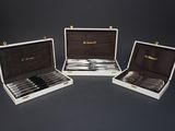 three silver plated knives in a case on a black surface