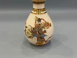 a small vase with a painting on it sitting on a table