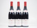 trois bouteilles de vin rouge posées l'une à côté de l'autre sur une surface blanche