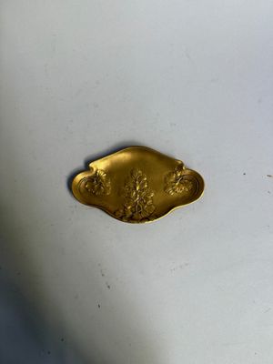 un objet doré posé sur une surface blanche, sur fond bleu