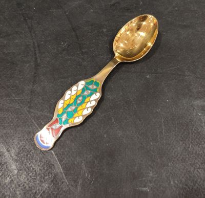 a gold spoon with a colorful fish design on it