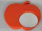 an orange apple shaped mirror sitting on a white surface