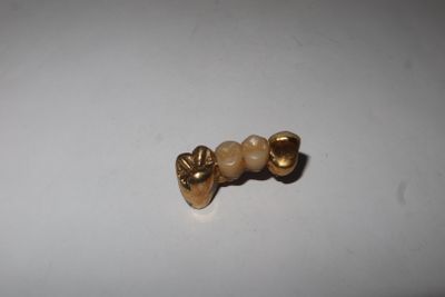a close up of a gold bead on a white surface