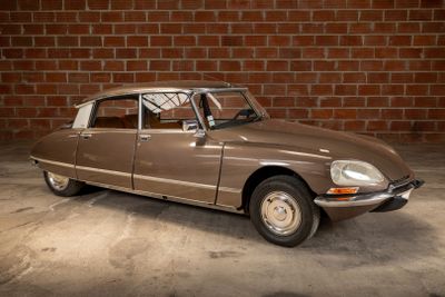 a brown car that is parked in front of a brick wall