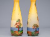 pair of yellow vases with trees painted on them sitting on a table