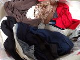 a pile of clothes sitting in a basket on a bed