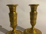 two gold candlesticks sitting on a white surface