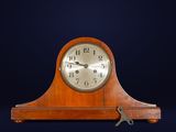a small wooden clock with a key on top of it
