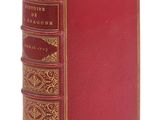 un vieux livre à la couverture rouge et à la bordure dorée