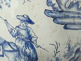 a blue and white vase with a picture of a man riding a horse