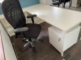 a white desk with a black chair next to it