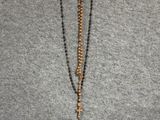 collier orné de perles et d'une croix suspendue à son cou