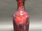 a red vase sitting on a table with a gray background
