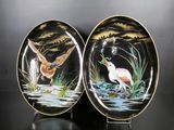 two plates with birds painted on them sitting on a table
