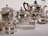 a silver tea set on a table with other silver items