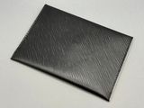 un gros plan d'un portefeuille noir posé sur une surface blanche