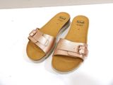 pair of women ' s rose gold sandals with buckles on white surface