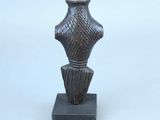 une petite statue représentant un vase posée sur un petit socle