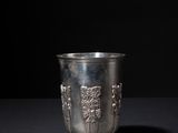 a silver cup sitting on a table with a black background