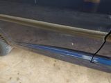a close up of a car door handle with a cat in the background