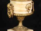 a white and gold urn with a lion head on it