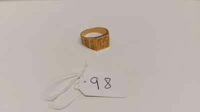 une bague en or posée sur une surface blanche, avec une étiquette de prix
